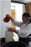 Age, contadina del Nord dell’Albania, nel costume tradizionale, riempie recipienti della grappa distillata in proprio (Foto: USP/Cospe.org)