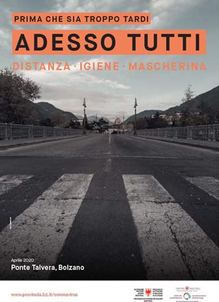 Scattata nell'aprile 2020, la fotografia in bianco e nero mostra il Ponte Talvera di Bolzano completamente deserto. L’immagine è accompagnata dallo slogan: Prima che sia troppo tardi. Adesso tutti. Distanza, igiene, mascherina.