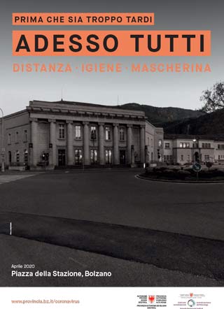 Scattata nell'aprile 2020, la fotografia in bianco e nero mostra un’insolita Piazza della Stazione di Bolzano senza traffico né persone. L’immagine è accompagnata dallo slogan: Prima che sia troppo tardi. Adesso tutti. Distanza, igiene, mascherina.